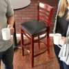 Lancaster Table & Seating Mahogany Ladder Back Bar Height Chair With Black Padded Seat